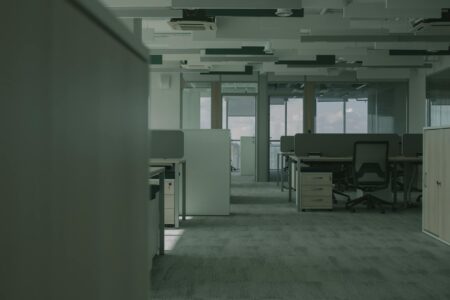 Empty modern office space with vacant desks and chairs showing reduced workplace occupancy