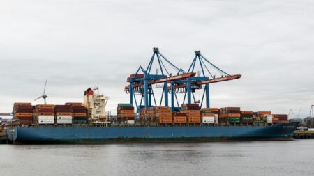 Major Shipping Companies Reduce Fleet Size Amid Overcapacity Crisis Large container cargo ship docked at industrial port with shipping containers