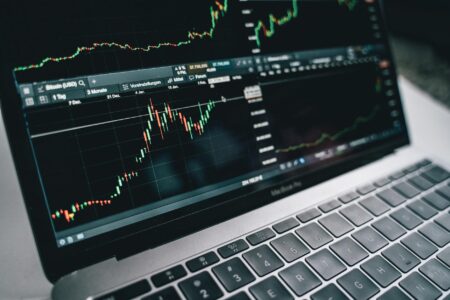 Multiple computer monitors displaying financial trading charts and market data