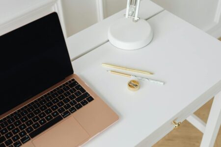 Person working remotely on laptop at home office desk with paperwork