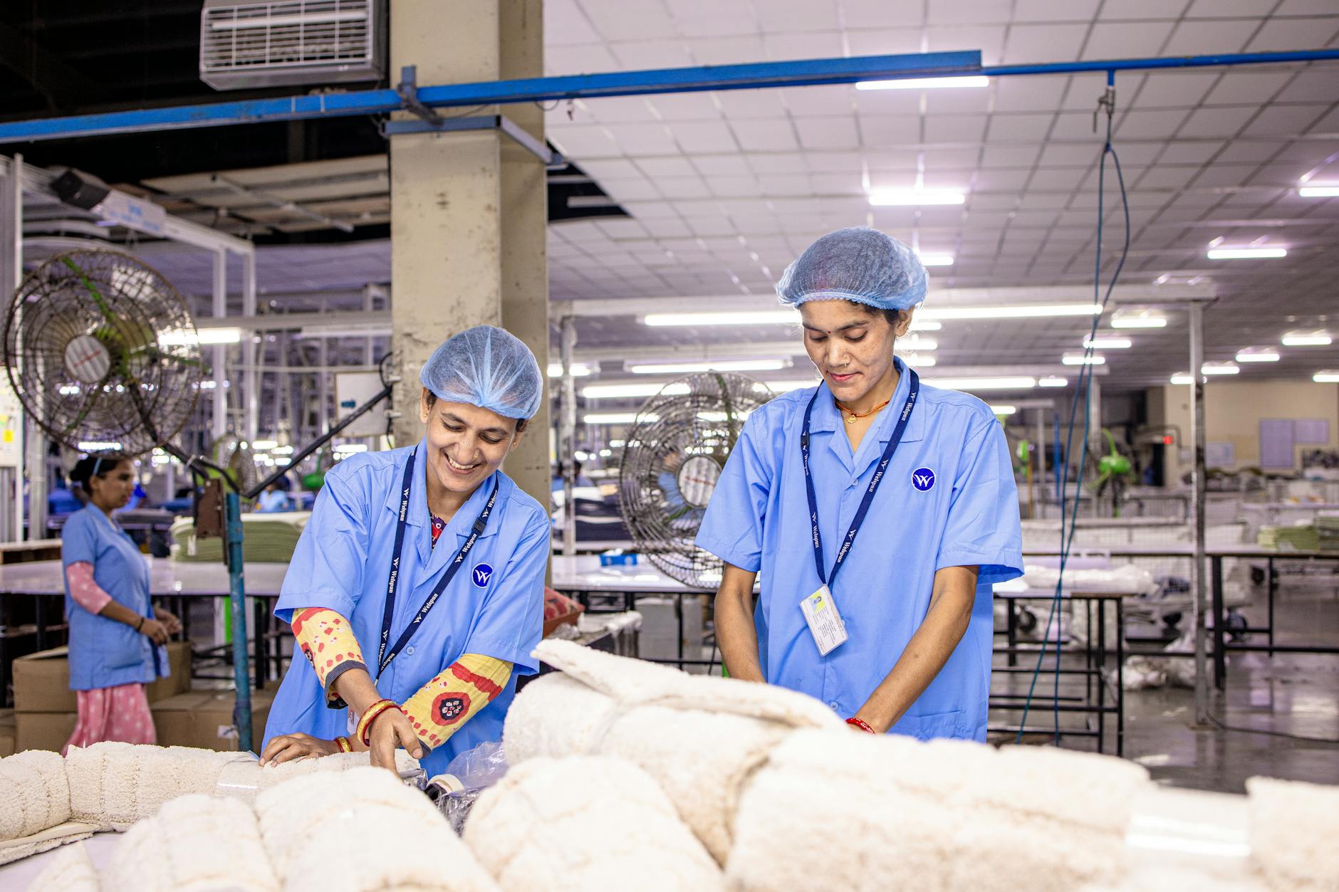 Textile factory workers operating industrial sewing machines in manufacturing facility