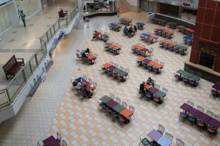 Empty retail corridor in shopping mall with vacant storefronts and minimal lighting