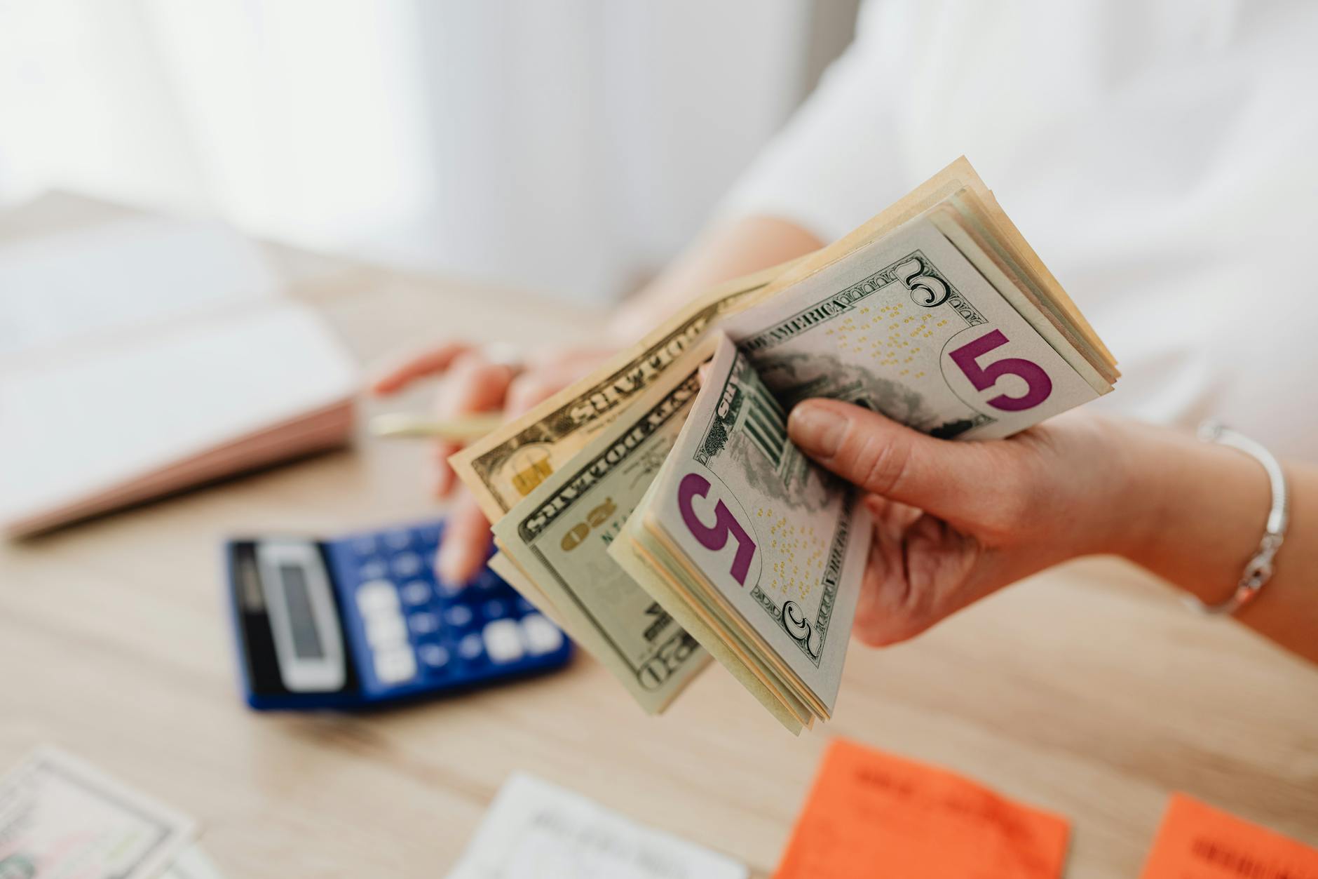 Hands counting dollar bills representing investment flows and capital allocation