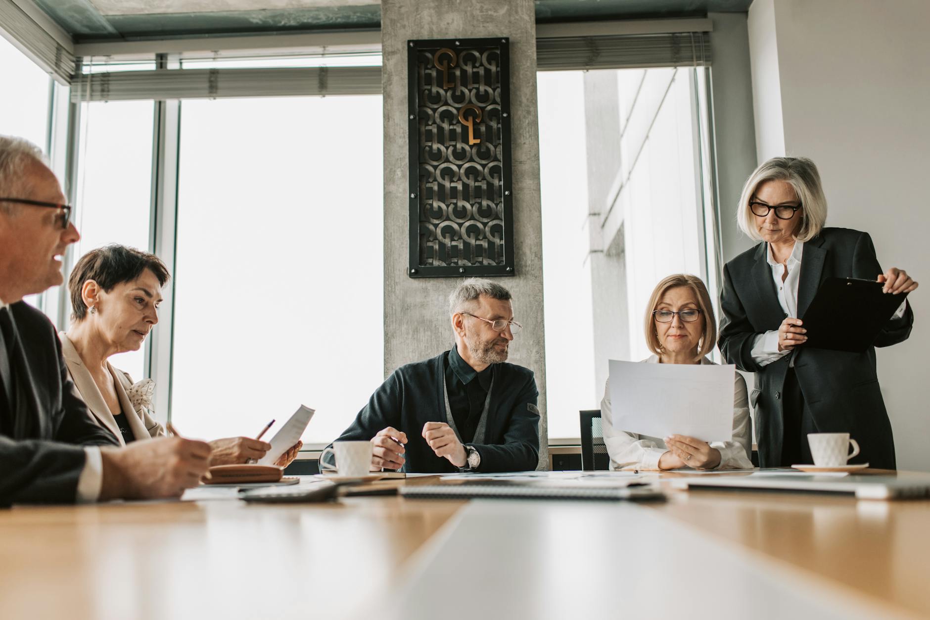 Professional business meeting in modern boardroom with executives discussing financial documents