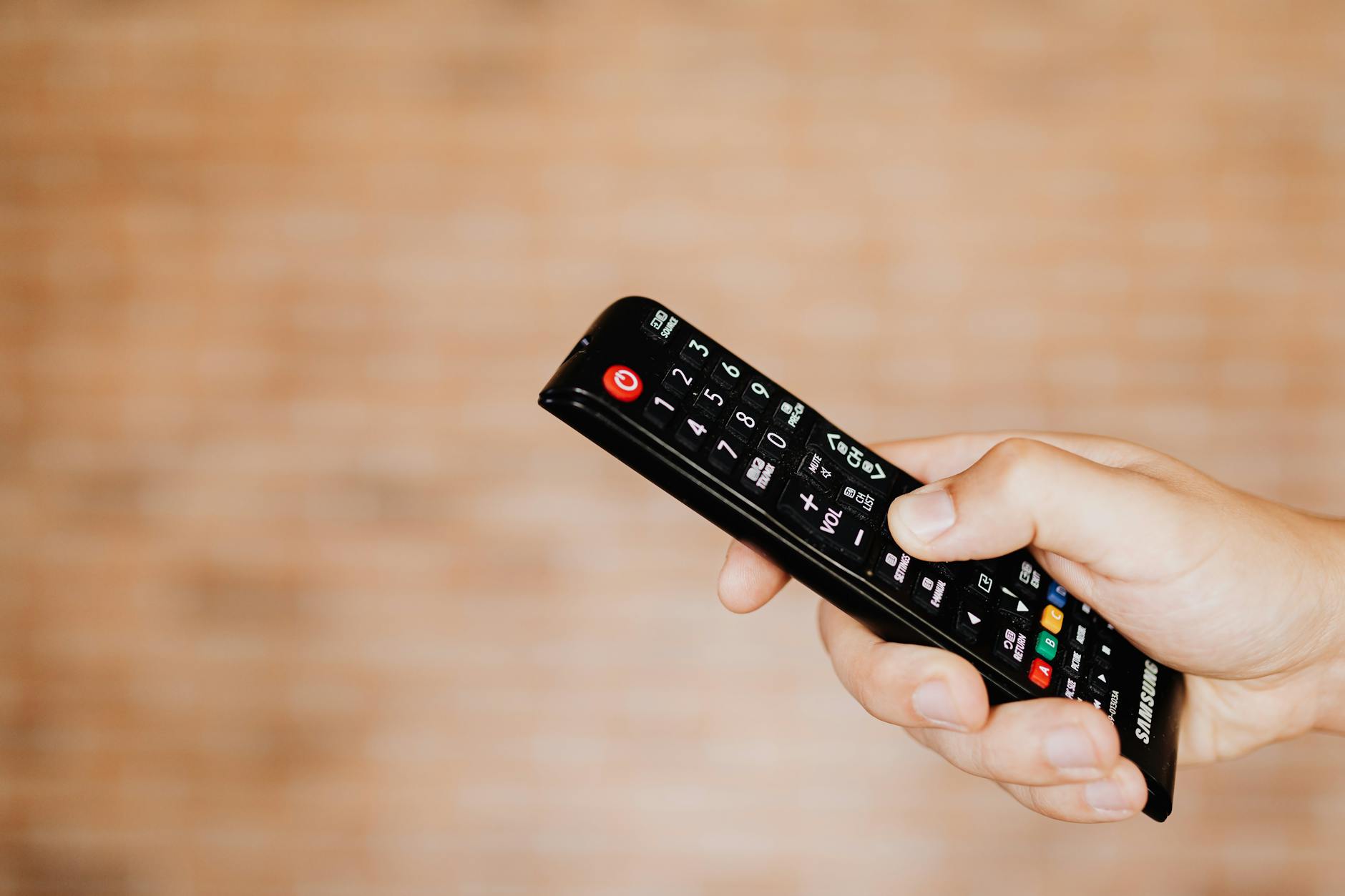 Hand holding streaming device remote control with multiple service buttons