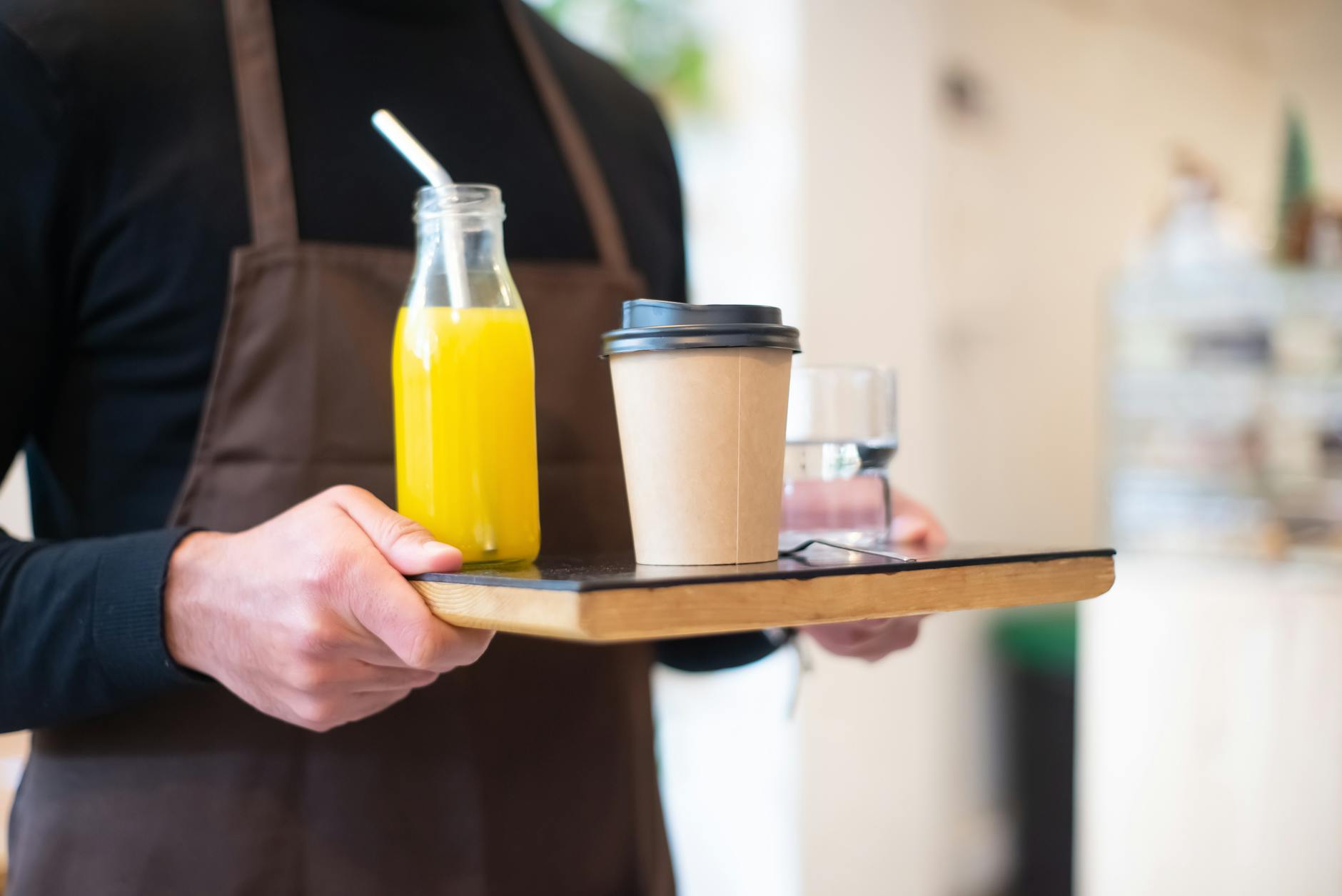 Barista preparing coffee order behind counter at busy coffee shop