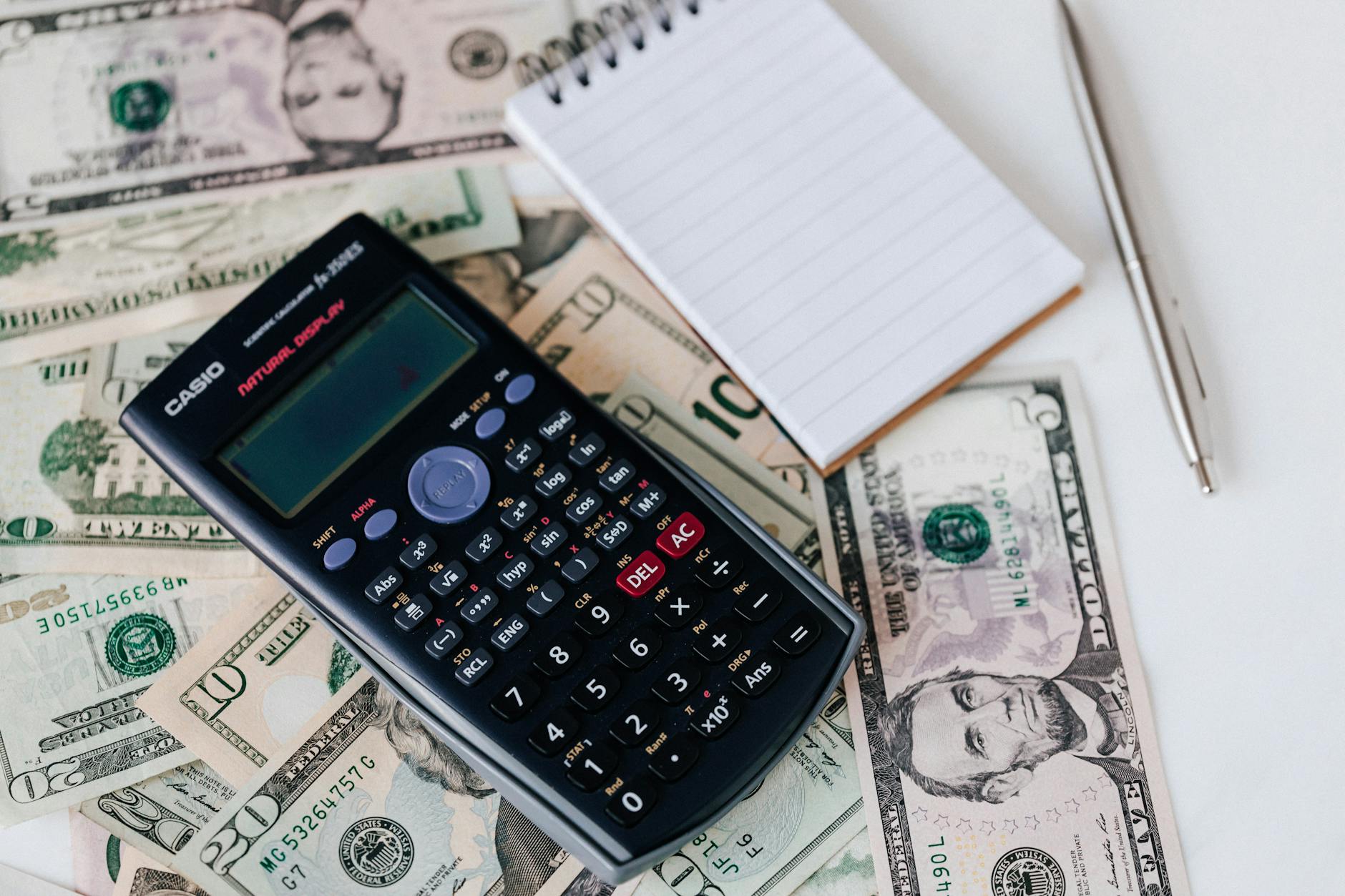Financial calculator with dollar bills and investment paperwork