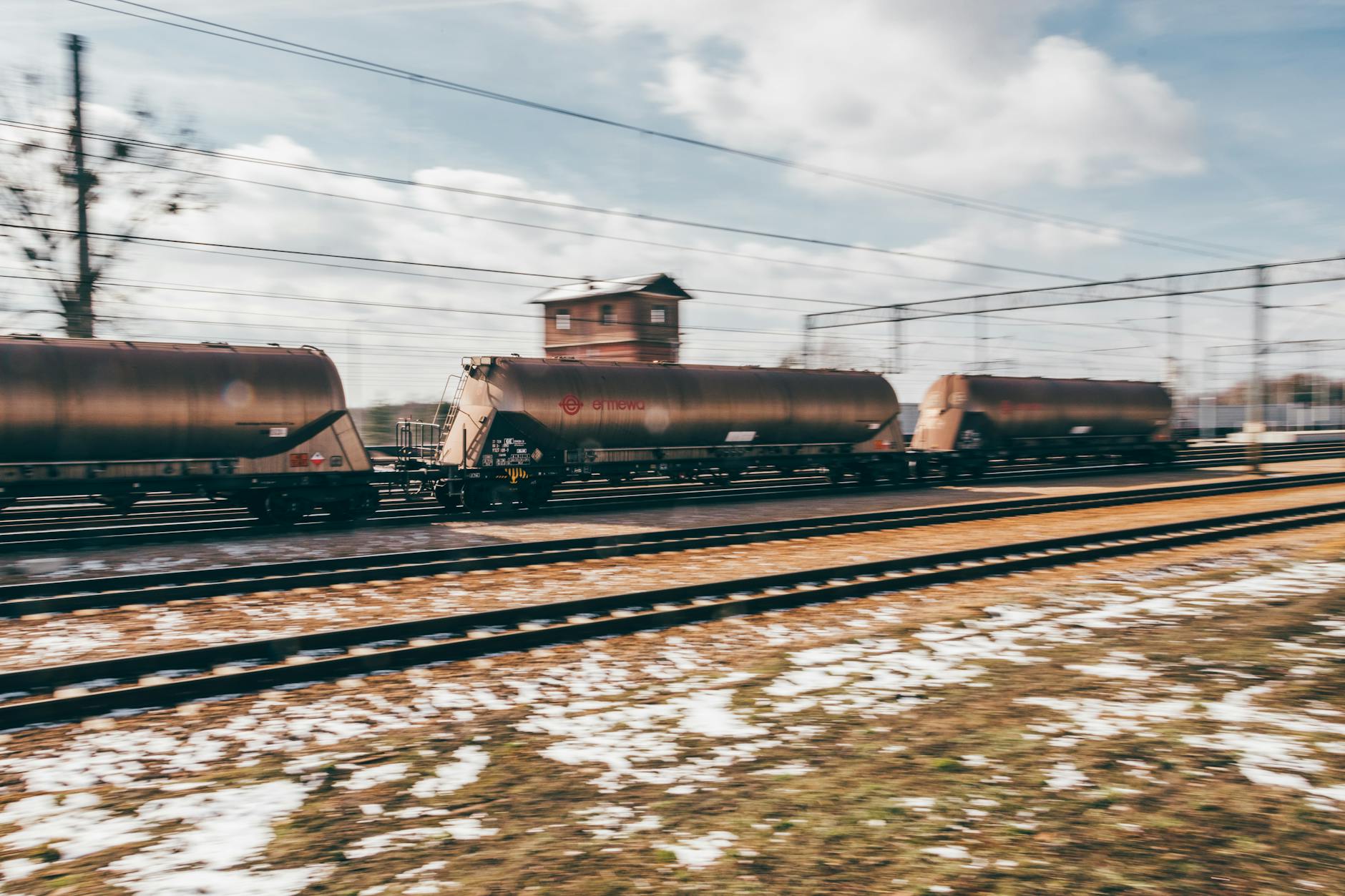 Long freight train carrying industrial cargo through rural landscape representing logistics infrastructure