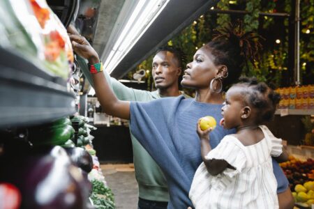 A family shopping in a grocery store aisle, representing food budget pressures on low-income households