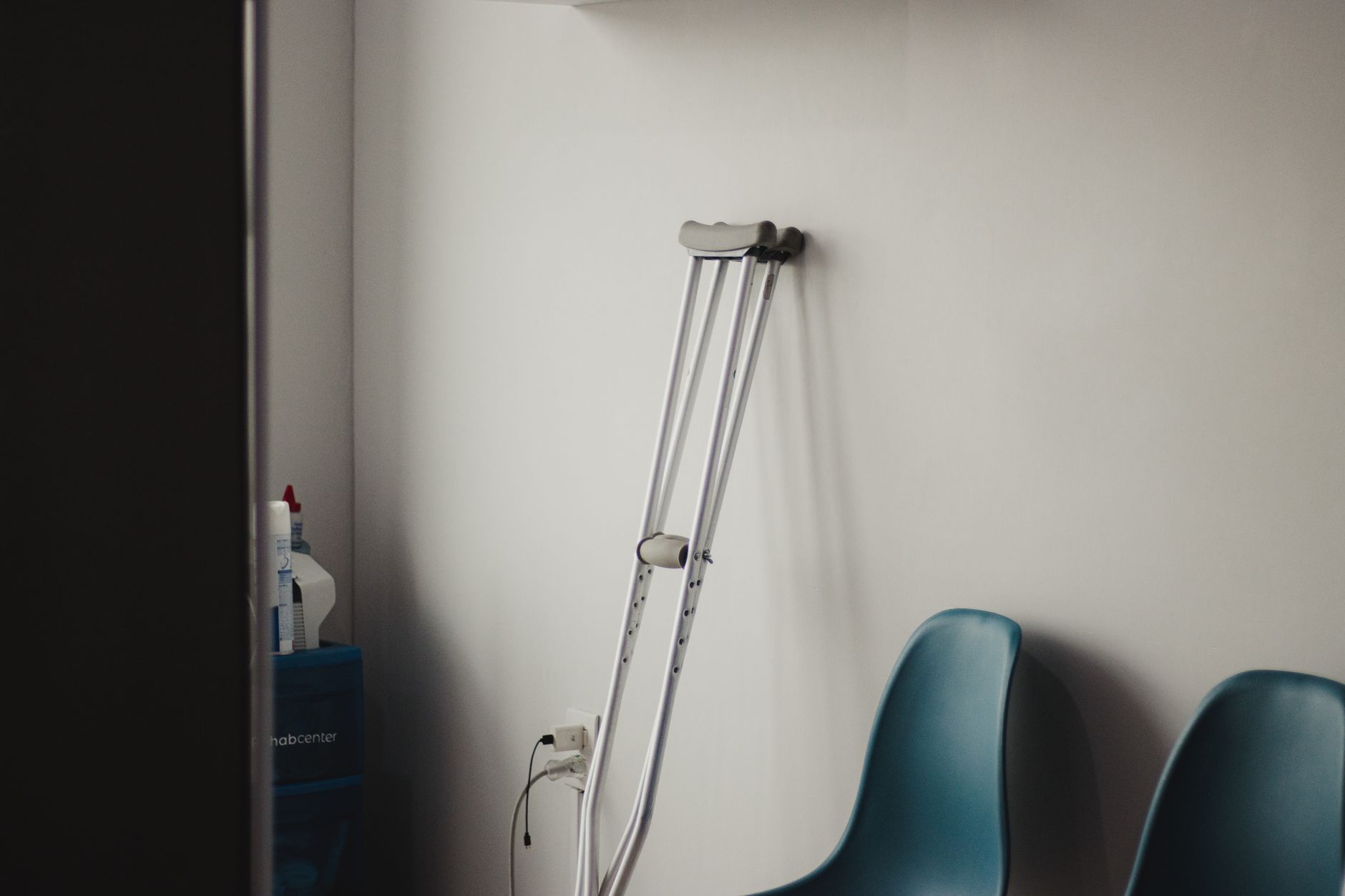 A sparse medical waiting room with empty chairs, representing long wait times at community health centers for low-income patients