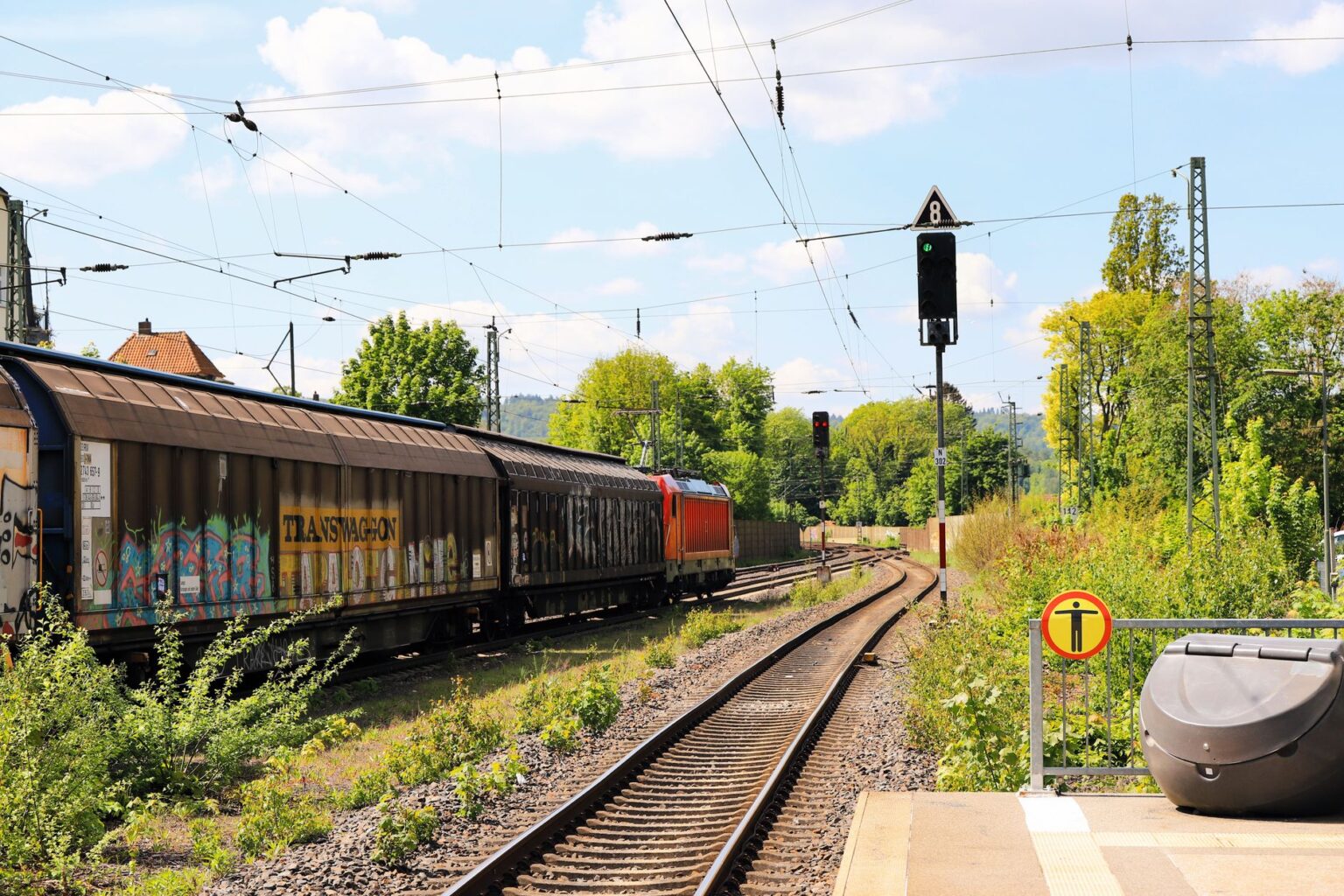 A long freight train carrying cargo containers across an open rail corridor