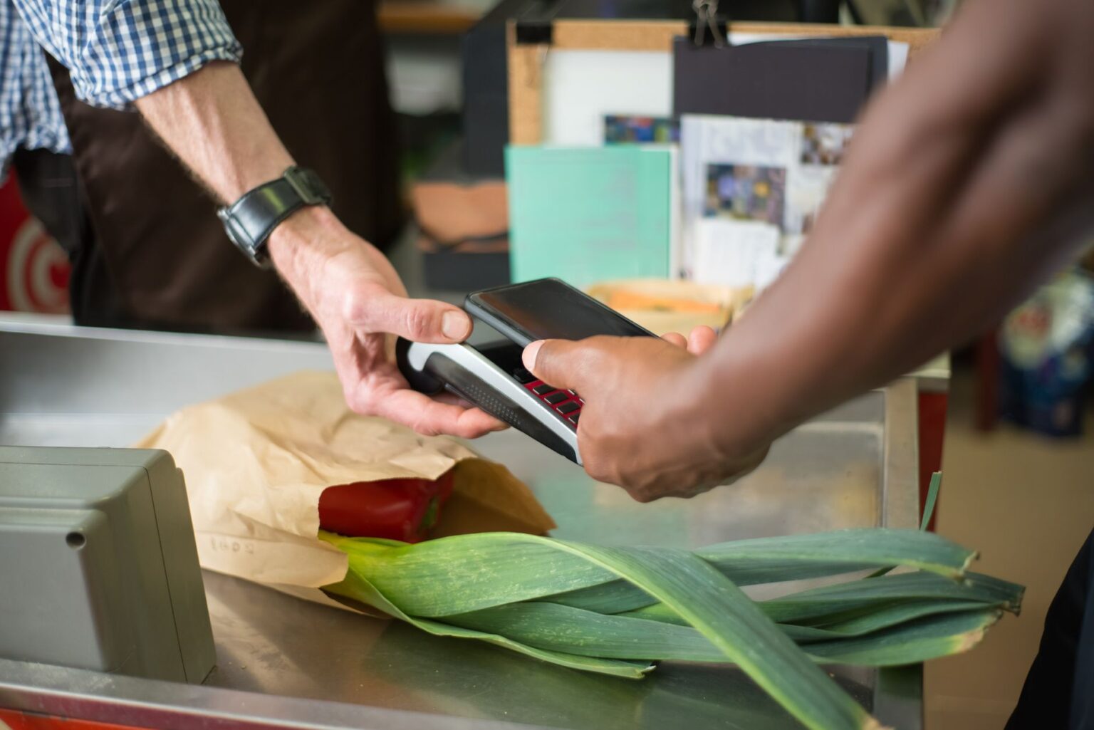 A shopper swiping a loyalty card at a grocery store checkout counter