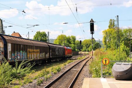 A long freight train carrying cargo containers across an open rail corridor