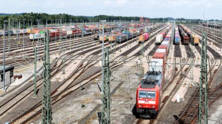 A freight train moving along rail tracks through an industrial corridor