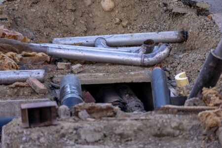 Aging underground water pipes showing wear and corrosion beneath a city street