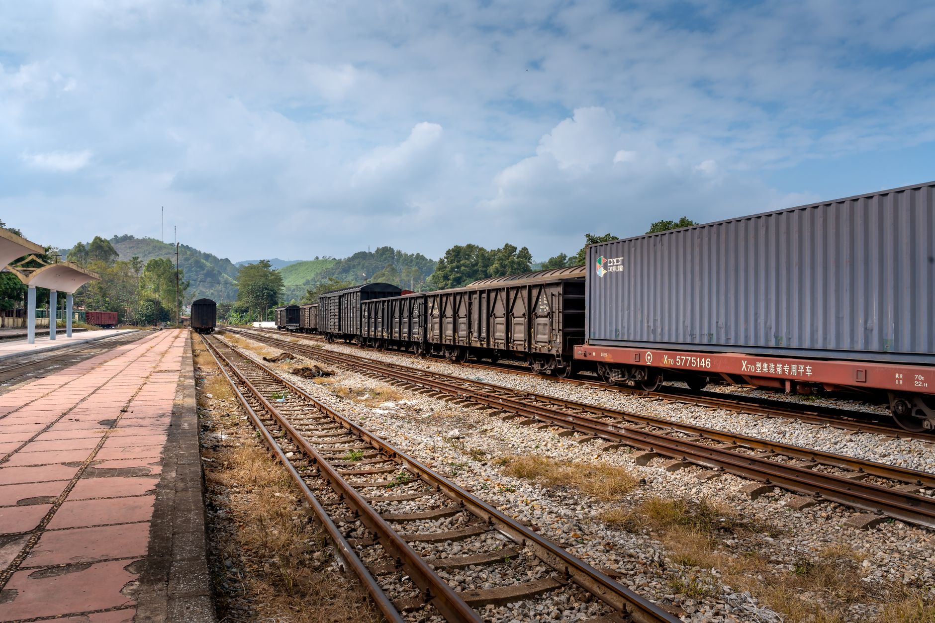 Freight train carrying intermodal shipping containers through an inland rail yard