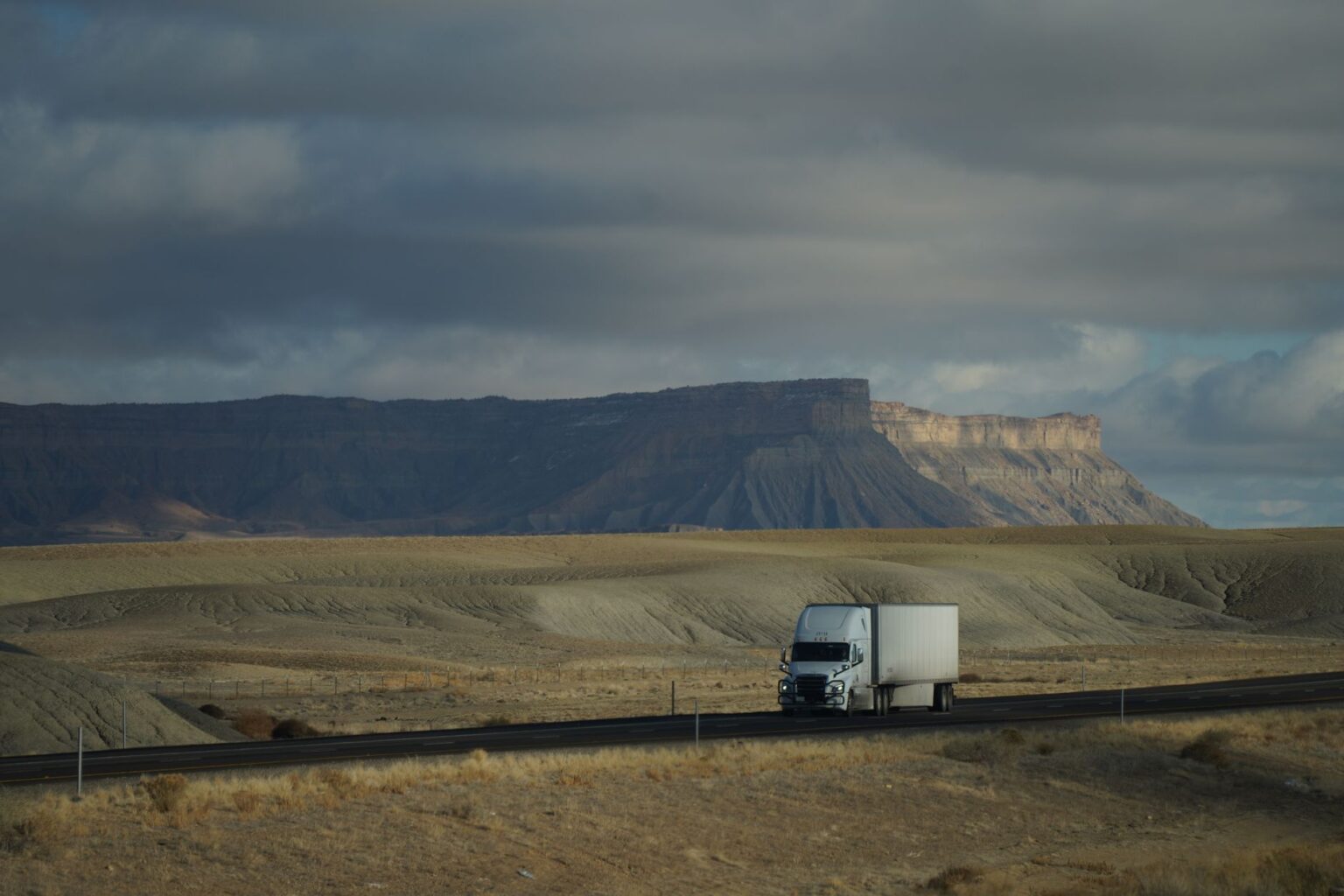 Long-Haul Trucking Shortages Deepen as Driver Retirement Wave Crests A long-haul semi truck driving along a wide American highway under open sky