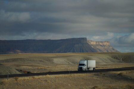 Long-Haul Trucking Shortages Deepen as Driver Retirement Wave Crests A long-haul semi truck driving along a wide American highway under open sky