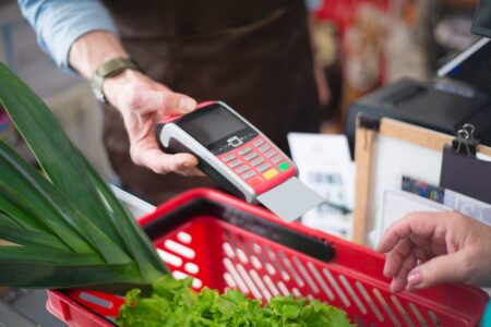 Grocery Loyalty Program Data Sales Quietly Fuel Retail Ad Networks Customer scanning loyalty card at grocery store checkout counter