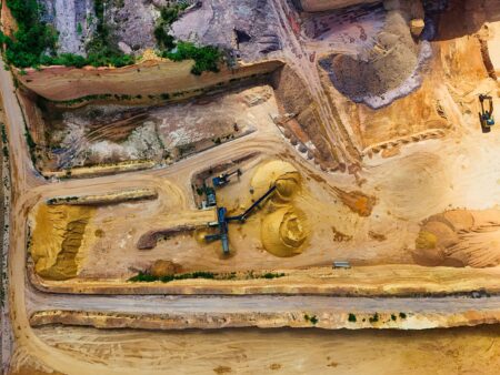 Lithium Glut Deepens as EV Demand Falls Short of Mining Bets Open-pit lithium mining operation with heavy machinery and excavated terrain