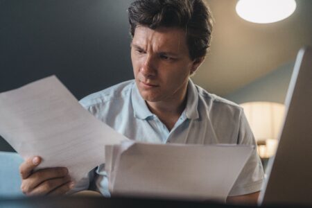 Federal Student Aid Processing Delays Stall Fall Enrollment Decisions College student reviewing financial aid documents at a desk