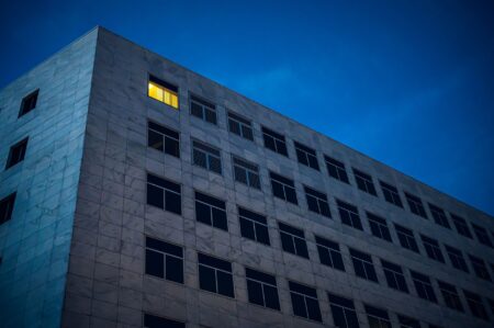 Office Vacancy Tax Proposals Gain Traction in Cash-Strapped Cities Empty office floors visible through glass windows of a downtown commercial tower
