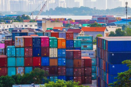 Port Congestion Fees Pile Up as Importers Reroute Around Tariffs Aerial view of a busy shipping port with stacked cargo containers
