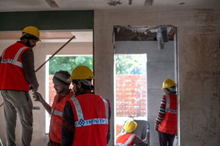 Construction workers on a residential building site with scaffolding and framing visible