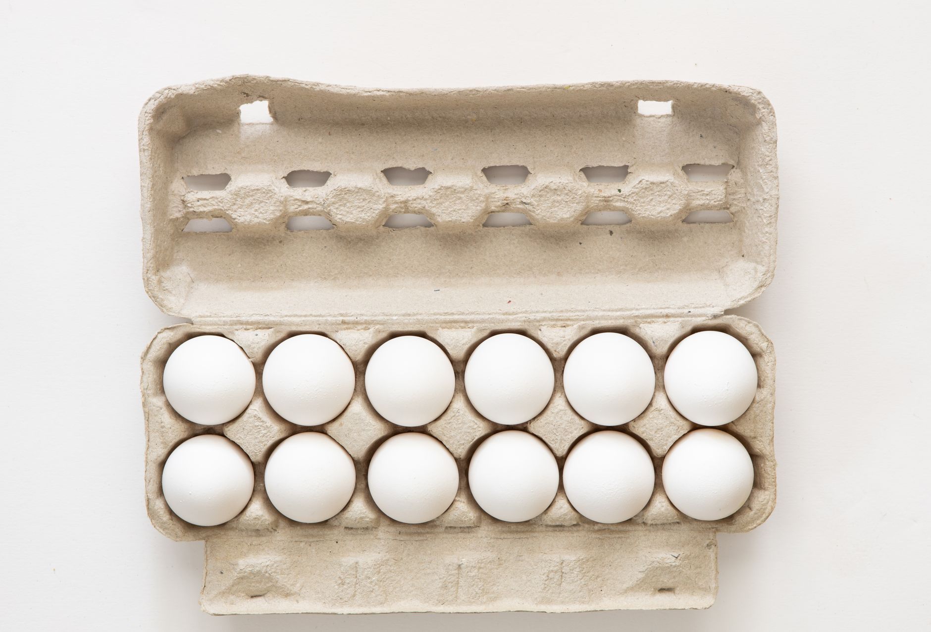 Close-up of a cardboard egg carton with white eggs on a store shelf